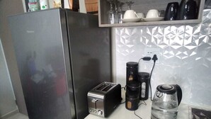 A kitchen with a stainless steel refrigerator, a toaster, a coffee maker, and a kettle on the counter. - Apartment In Rosebank Johannesburg (Johannesburg)