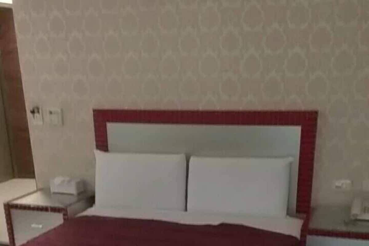 A neatly made bed with a red headboard and white pillows in a hotel room.