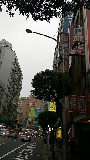 A street scene with buildings, a tree, and a street lamp. - Meets Happy Hotel (New Taipei City)