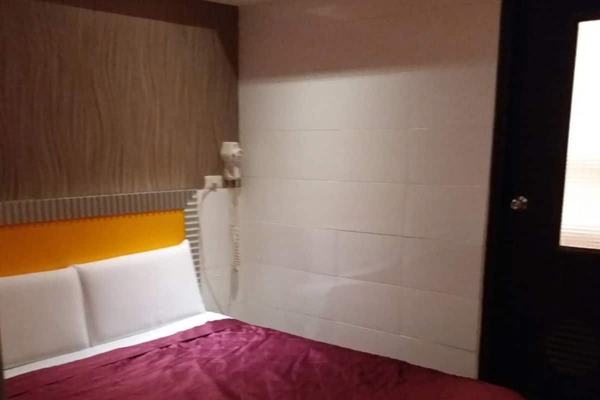 A bedroom with a bed, a headboard, a wall-mounted heater, and a door.