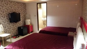 Een hotelkamer met twee bedden, een televisie, een bureau en een rode kast.