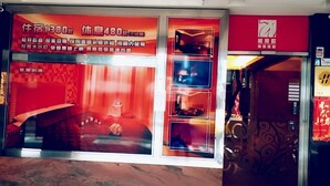 Een hotel met een rood-wit kleurenschema, met een grote etalage waarin meerdere kamers te zien zijn.