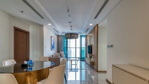 A spacious, modern hotel room with a large glass dining table, comfortable seating, a large window with a view, and a sleek, minimalist design. - Hoasun Des Arts Landmark 81 (Ho Chi Minh City)