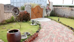 A paved pathway leading to a wooden gate, surrounded by a stone wall, with a large pot and potted plants along the path. - Remember Sea View B&B (Huxi)