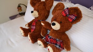 Two brown teddy bears with plaid bows sitting on a bed with white sheets and a purple headboard. - Remember Sea View B&B (Huxi)