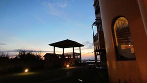 A gazebo with a view of the sunset over the water, a building with a balcony, and a small light in the foreground. - Remember Sea View B&B (Huxi)