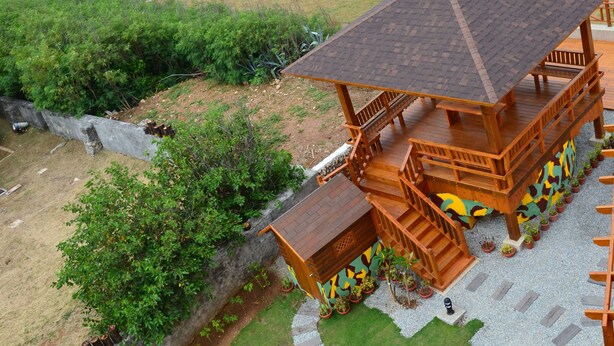 A wooden deck with a view of the ocean, surrounded by a well-maintained lawn and a stone pathway. - Remember Sea View B&B (Huxi)