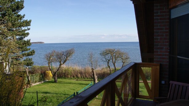 A wooden deck with a view of a body of water and a distant landmass. - Blick auf Vilm (Putbus)