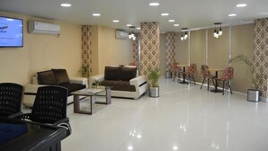 Un hall d’hôtel moderne avec un comptoir d’accueil, un espace salon et des murs décorés de motifs.