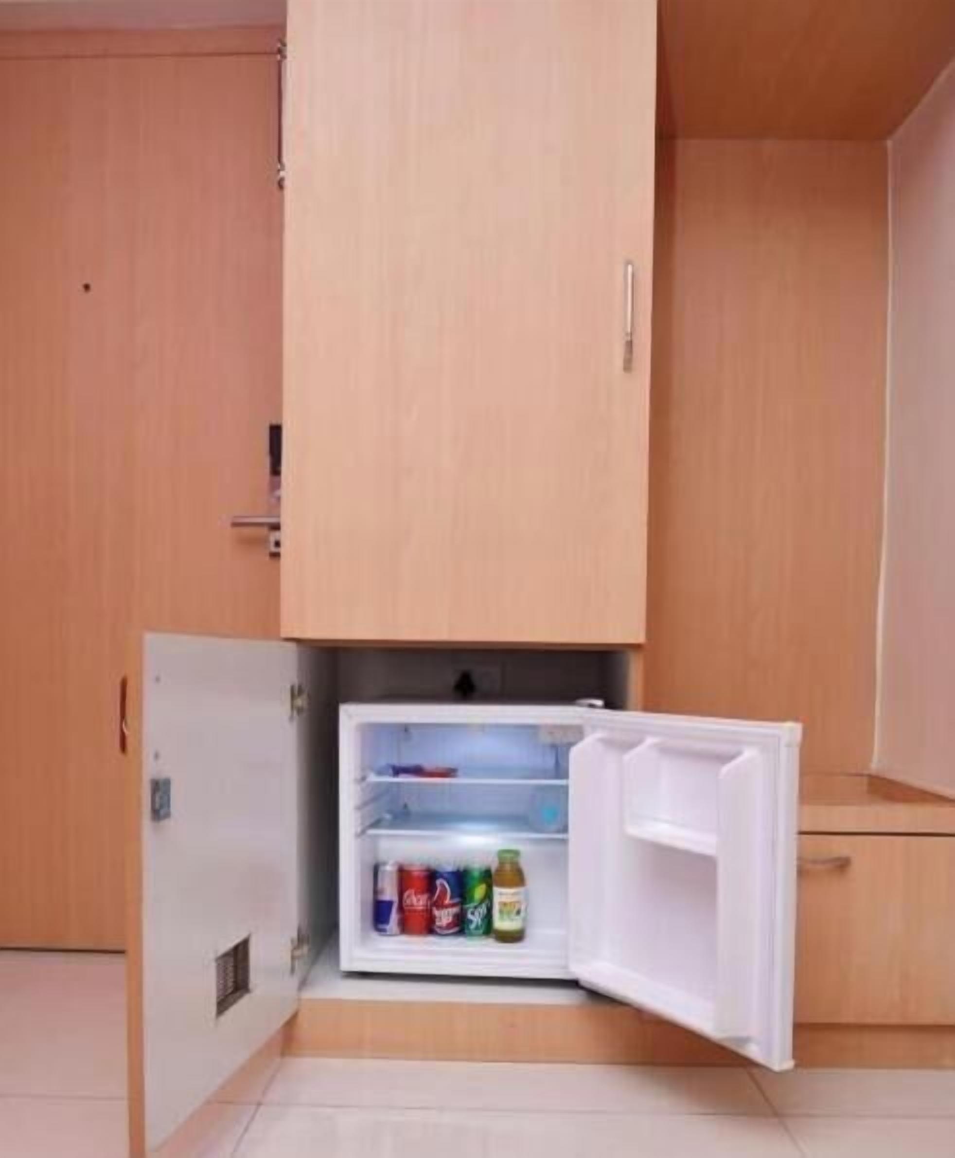 A compact kitchen with a built-in refrigerator, a wooden cabinet above, and a small countertop.