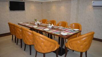 A conference room with a long table, six chairs, and a flat-screen TV on the wall.