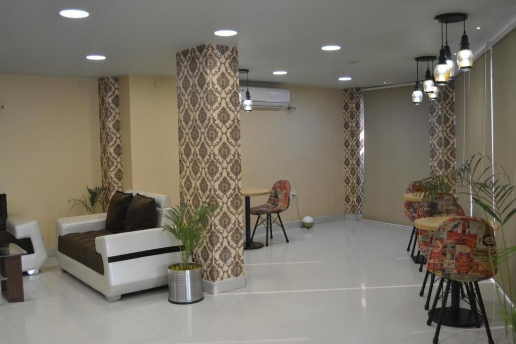 A spacious lobby with a sofa, chairs, a small table, and patterned wallpaper.