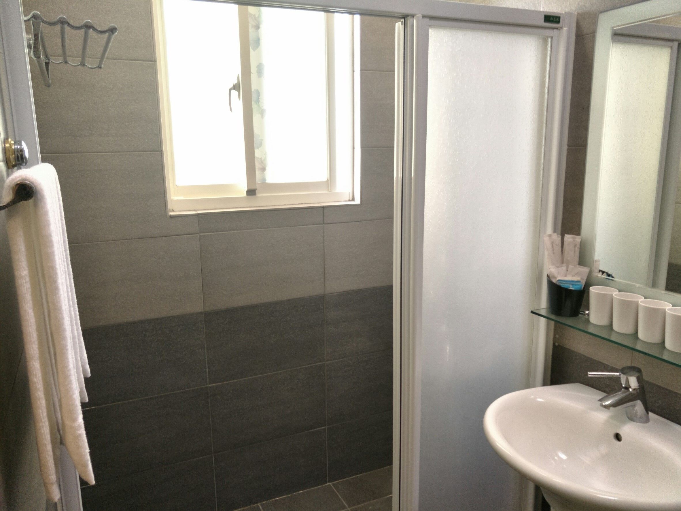 Une salle de bain avec une douche, un lavabo et une fenêtre.