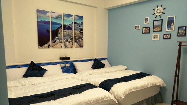 Un dormitorio con dos camas, una pared azul y un reloj.