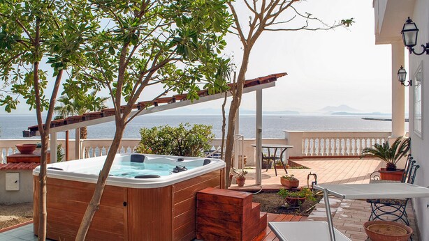 A hot tub on a balcony with a view of the sea.