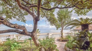 A pathway leading to a scenic overlook with a view of the sea and a distant cityscape.