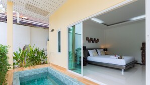 A modern bedroom with a large bed, a glass door leading to a balcony, and a small pool area. - Villa Oxavia (Rawai)