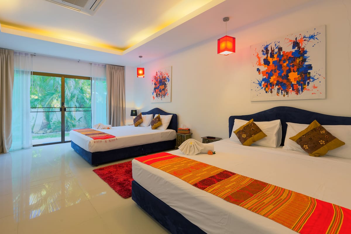 A hotel room with two beds, a large window with curtains, and artwork on the walls.