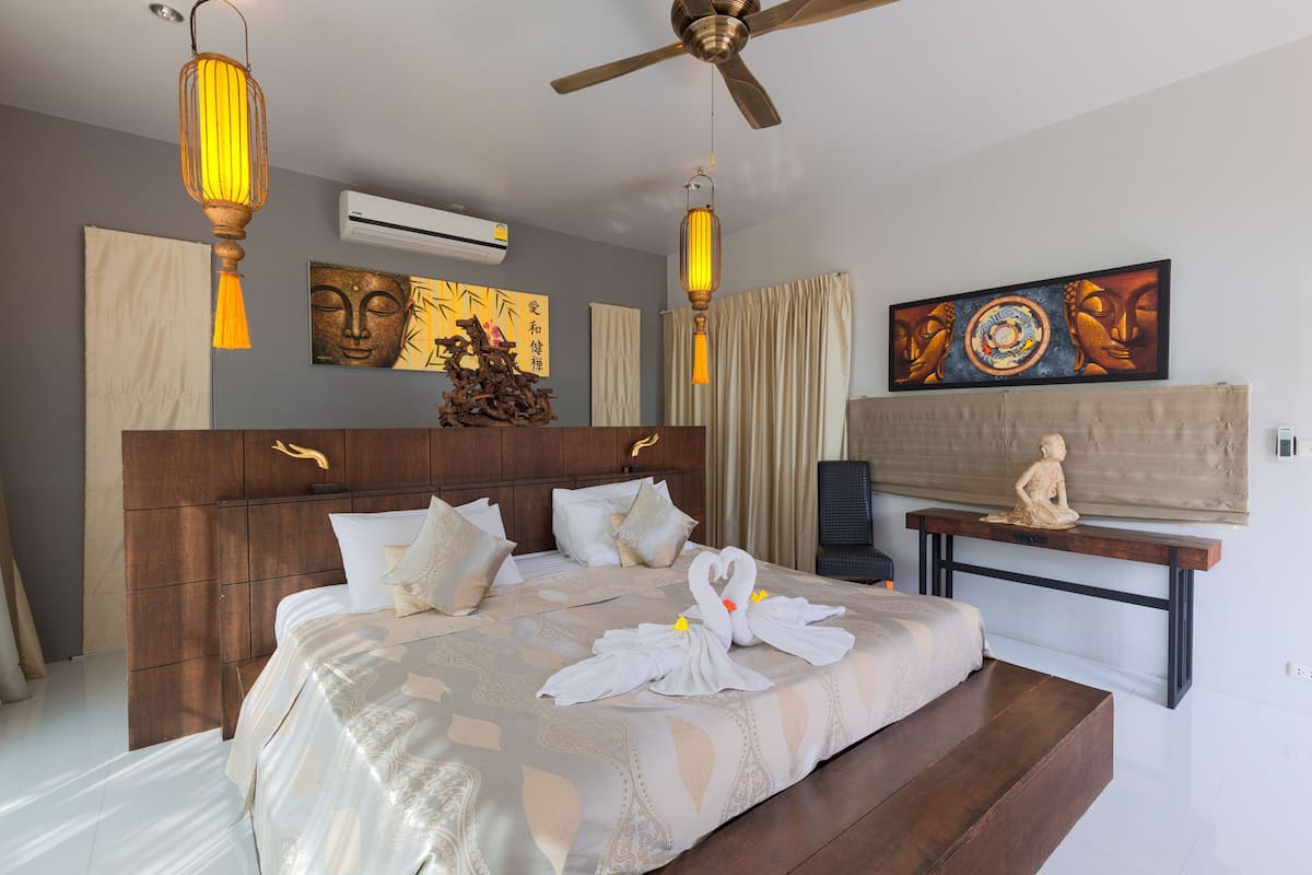 A modern hotel room with a large bed, wooden headboard, and a ceiling fan.