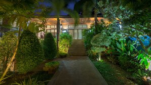 A modern building with a concrete pathway leading to a set of stairs, surrounded by lush tropical vegetation. - Villa Oxavia (Rawai)