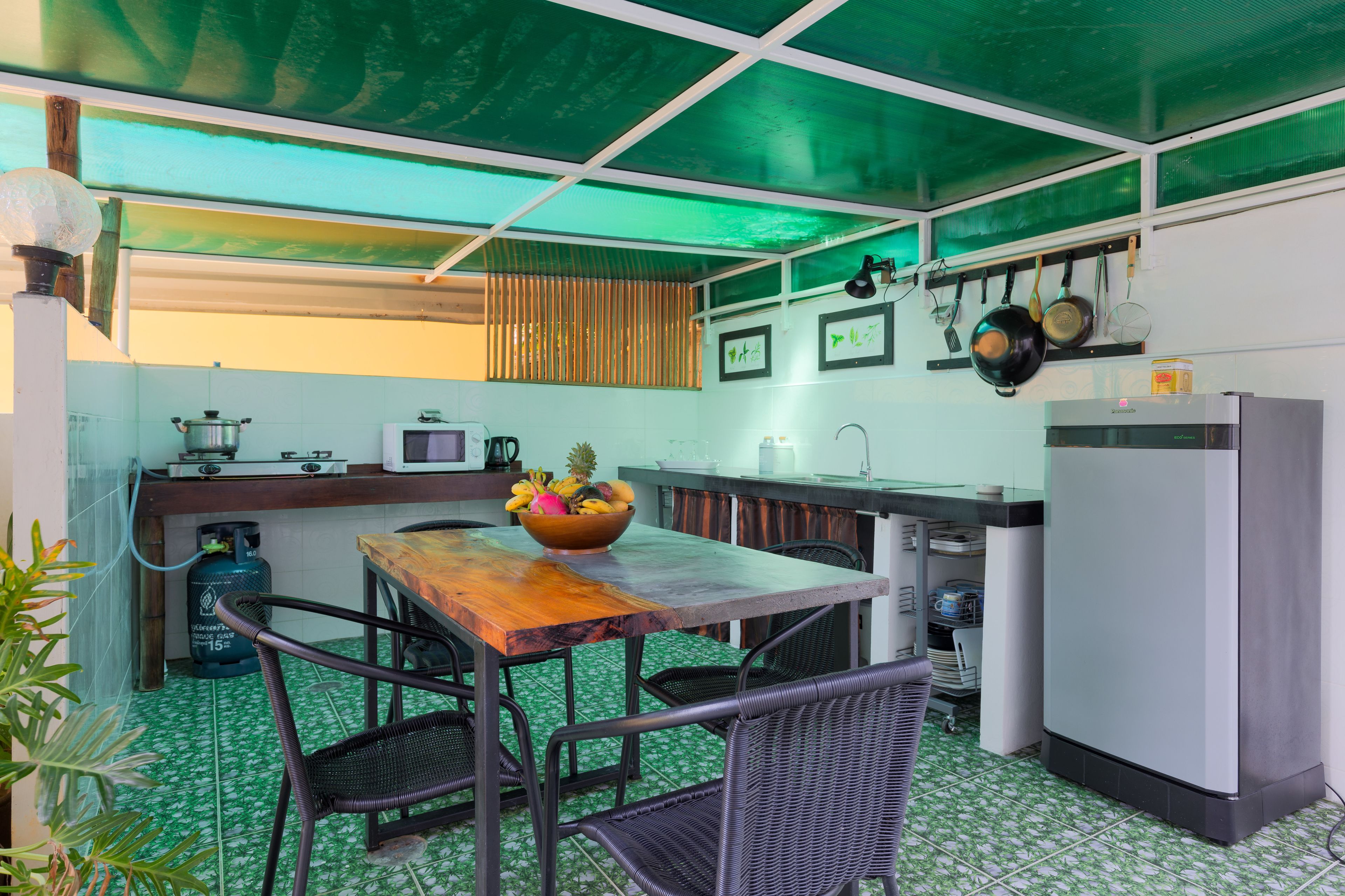 Een kleine keuken met een eettafel, stoelen, een koelkast en een gasfornuis.