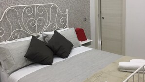 A neatly made bed with a white metal headboard, grey bedding, and a beige throw blanket. - Il Cuore di Napoli (Naples)