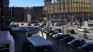 A busy street with parked cars and a large building with a dome in the background. - Il Cuore di Napoli (Naples)