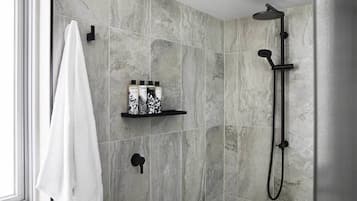A modern bathroom with a shower, a towel rack, and a shelf with toiletry bottles.