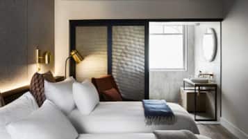 Una habitación de hotel moderna con una cama grande, un escritorio, una silla, una ventana y un baño.