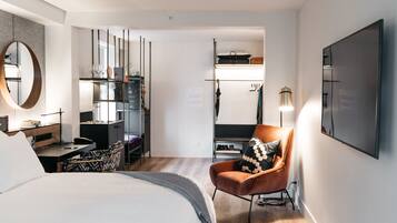 Una habitación de hotel moderna con una cama grande, un escritorio, una silla, un armario y un espejo.