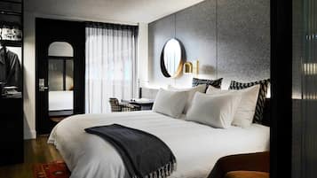 A modern hotel room with a large bed, a desk, and a wardrobe.