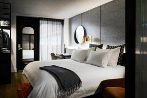 Una habitación de hotel moderna con una cama grande, un escritorio y un armario.