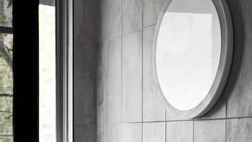 A modern bathroom with a round mirror, a wooden vanity, and a built-in sink.