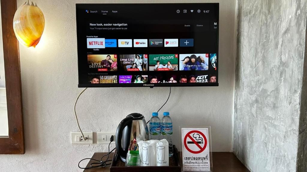 Un televisor montado en la pared muestra la interfaz de un servicio de streaming con diversas aplicaciones y contenido.