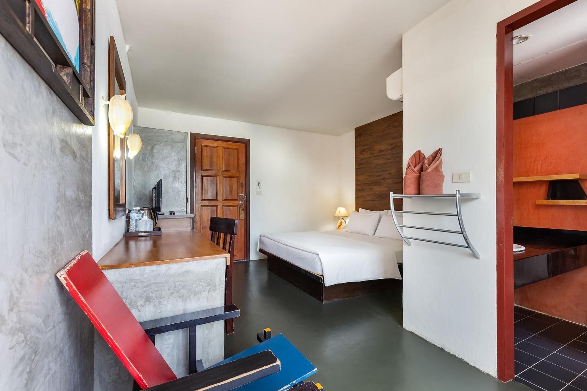 Une chambre d’hôtel de taille réduite, comprenant un lit, un bureau avec une chaise, une petite table et un miroir.