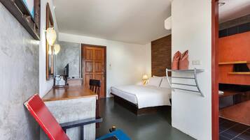 Une chambre d’hôtel de taille réduite, comprenant un lit, un bureau avec une chaise, une petite table et un miroir.