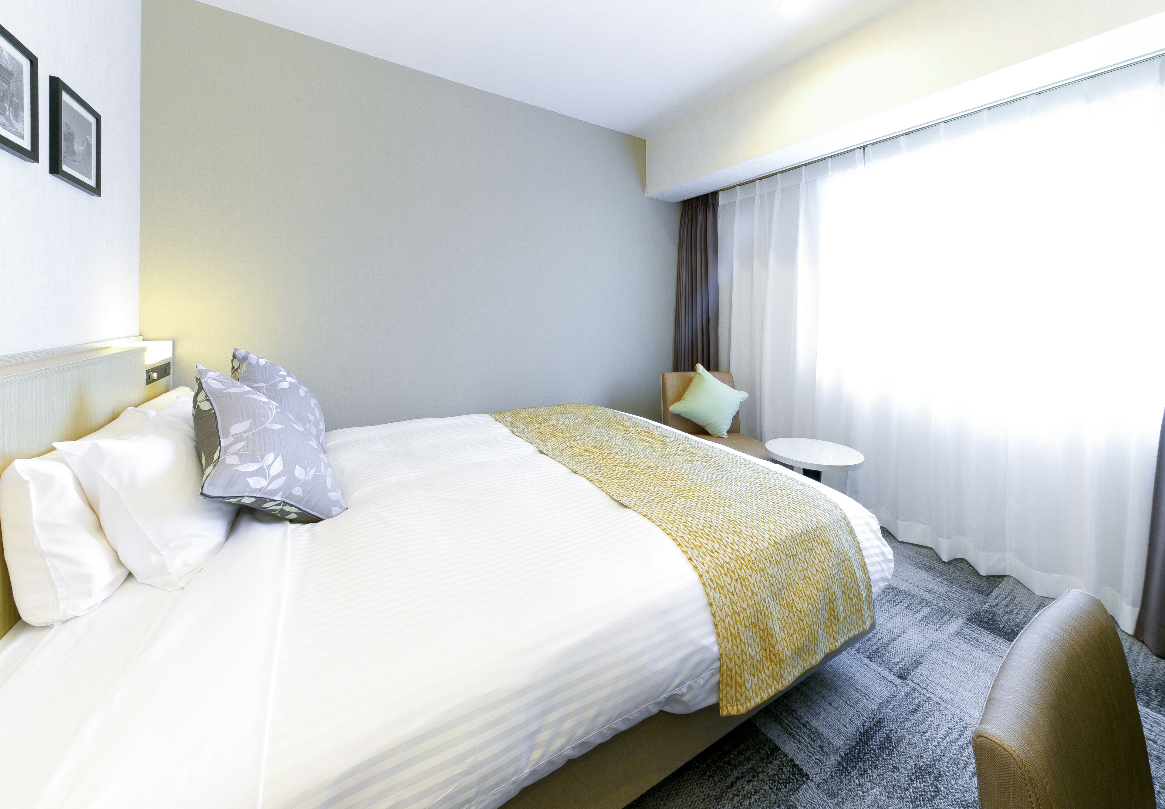 Una habitación de hotel con una cama bien hecha, una mesita redonda y una silla.