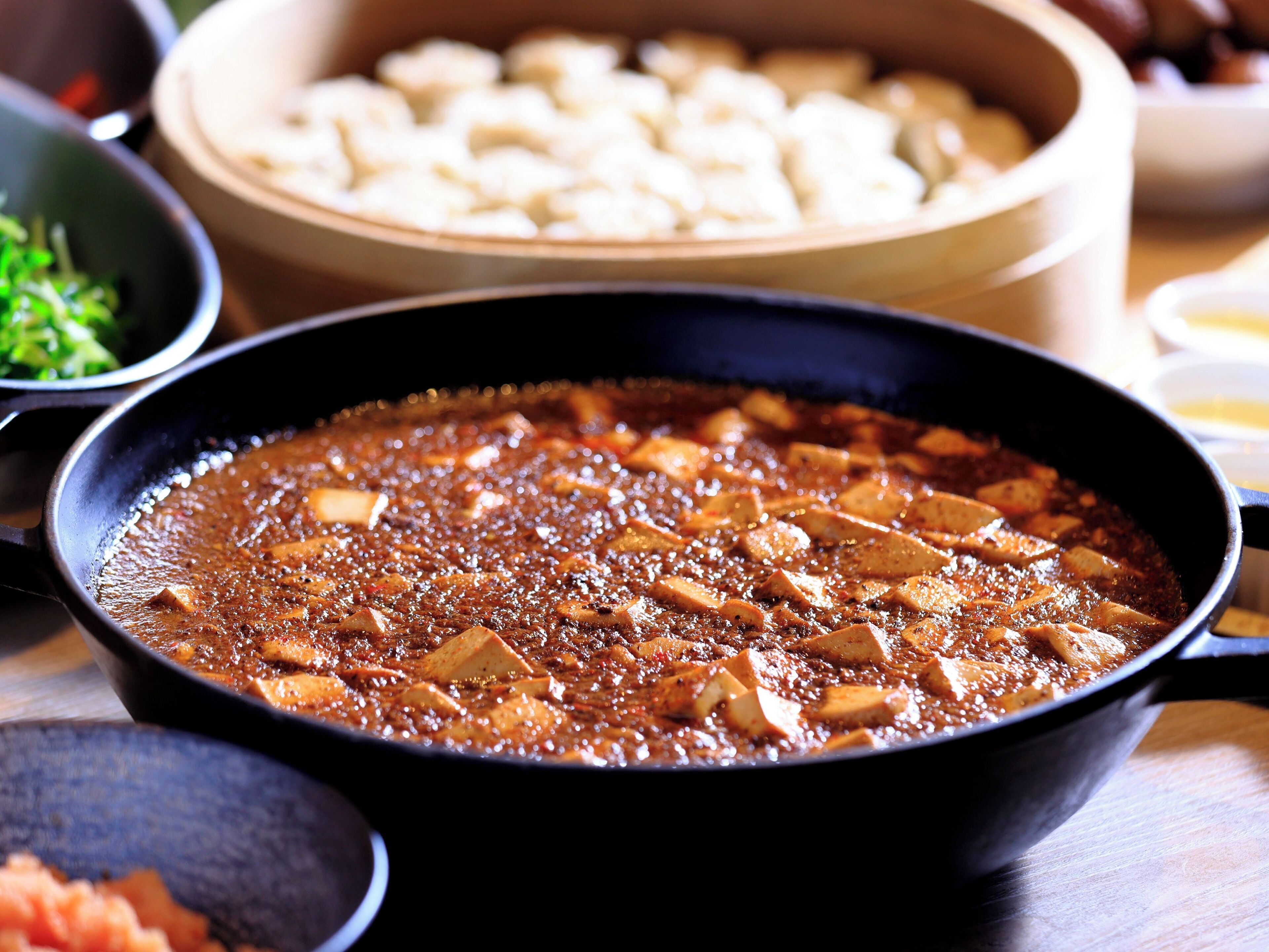 Primer plano de un plato con salsa oscura y abundante, y cubos de tofu.