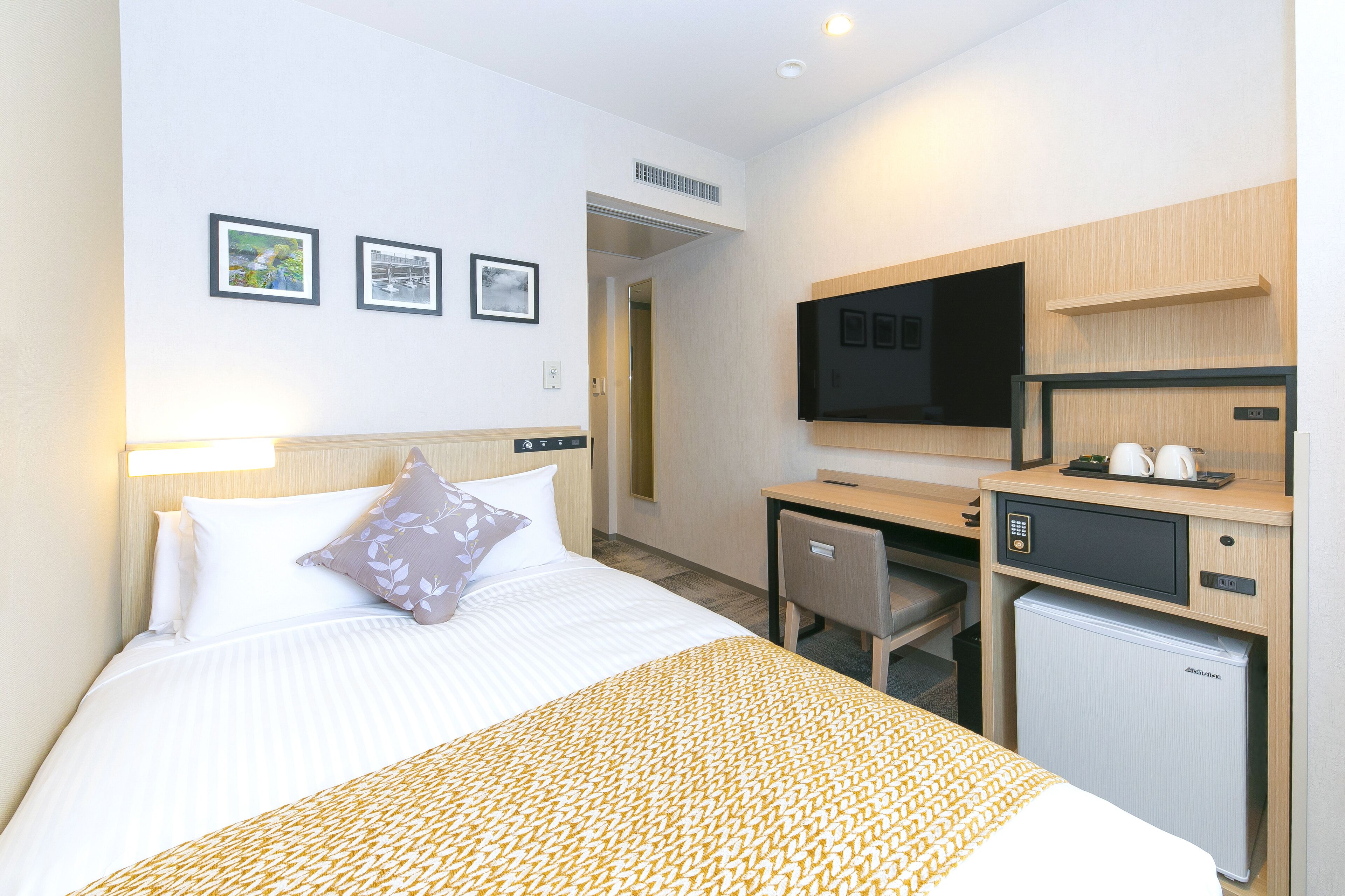 Una camera d'albergo con un letto, una scrivania, una televisione e un frigorifero.
