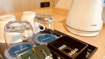 A tray with a coffee maker, two mugs, and a tea pot on a wooden surface.