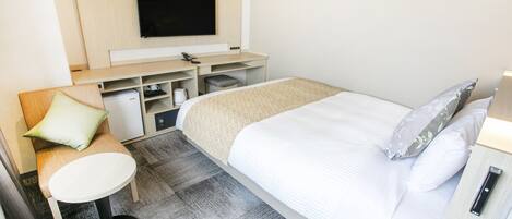 A hotel room with a bed, a desk, a chair, a TV, and a small table.