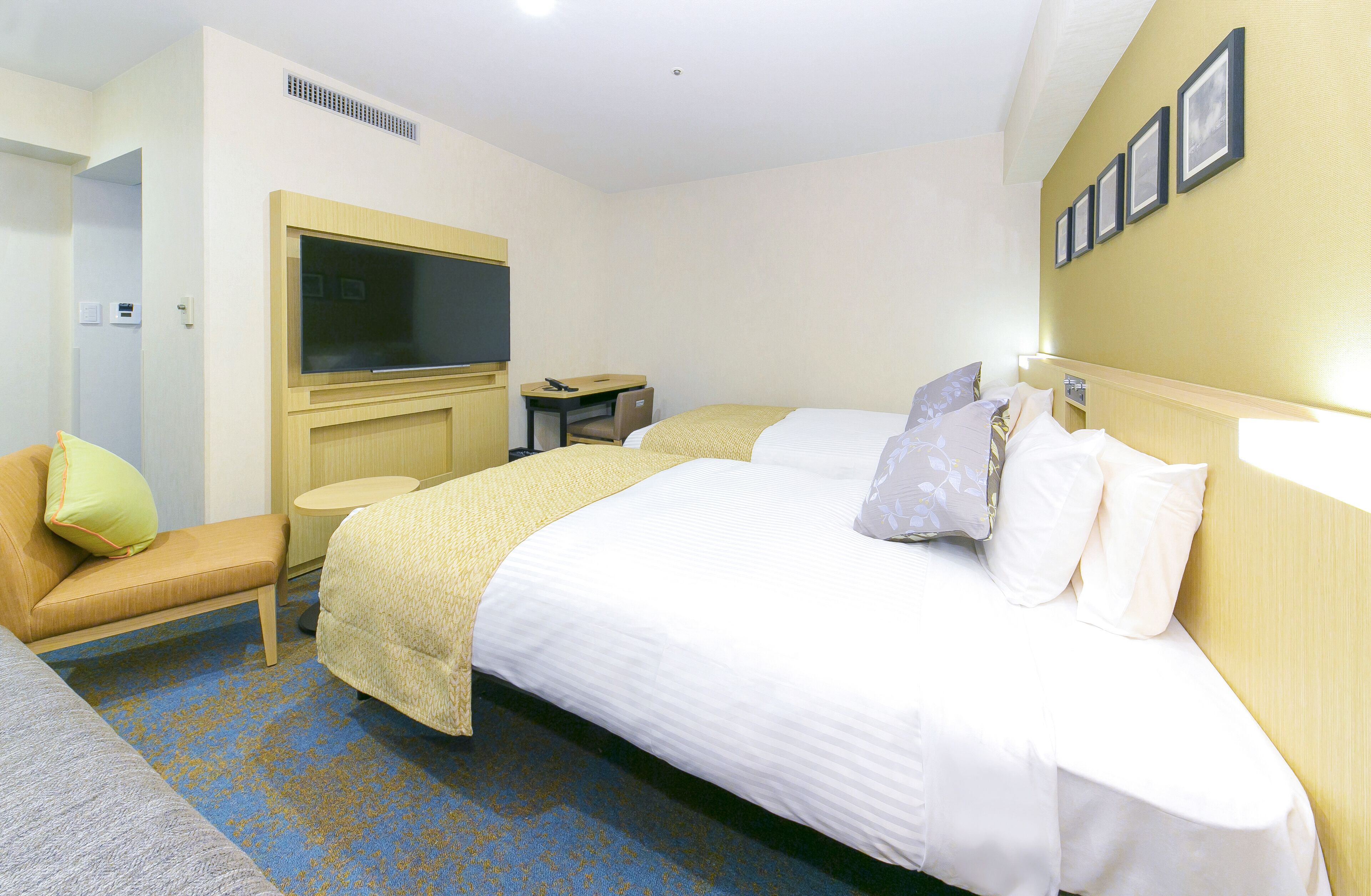 A hotel room with a bed, a desk, a TV, and a sofa.