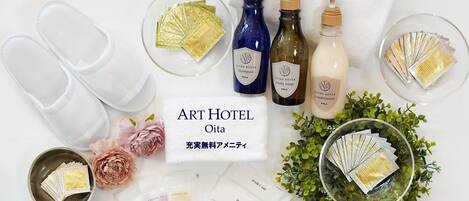 A variety of toiletries and personal care items arranged on a white surface, including slippers, bottles of shampoo, conditioner, body soap, and toothbrushes.