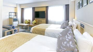 Hotellihuone, jossa on kaksi sänkyä, työpöytä, televisio ja pieni keittonurkkaus.