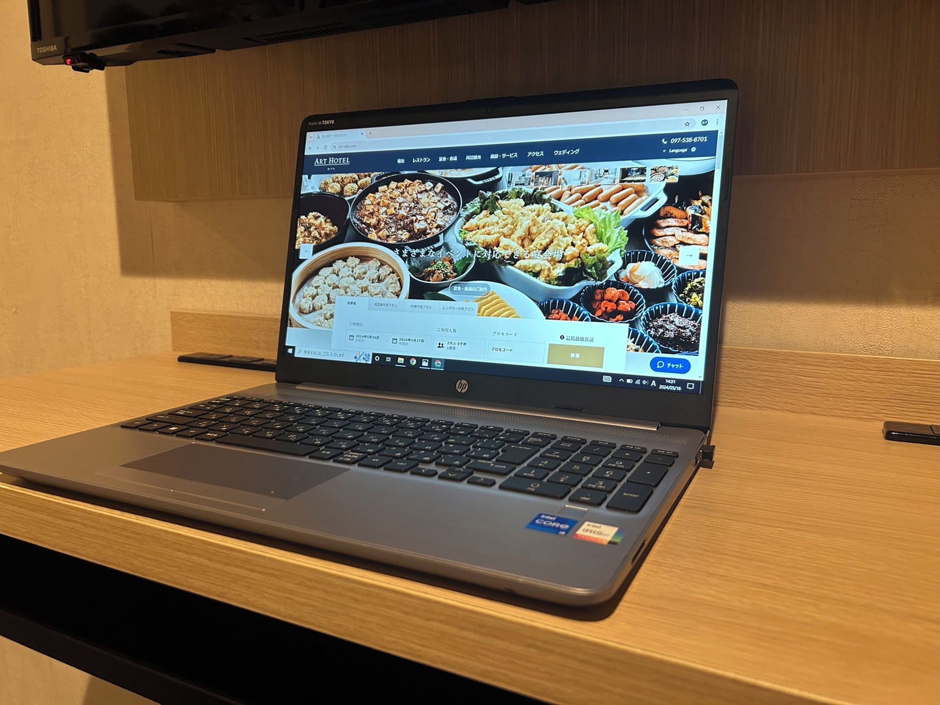 En Toshiba-laptop på et træbord med en webbrowser, der viser en restaurants hjemmeside.