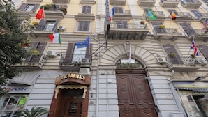 Hotel Garibaldi with a prominent entrance, balconies with plants, and multiple flags. - Garibaldi Suite (Naples)