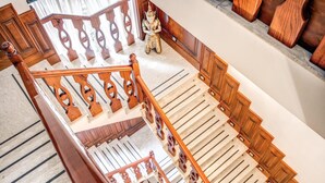 A grand staircase with ornate wooden railings and a decorative statue at the top. - Garibaldi Suite (Naples)