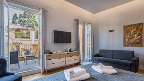 A modern hotel room with a large bed, a sofa, a TV, and a view of the outdoors. - President Gardens (Rome)
