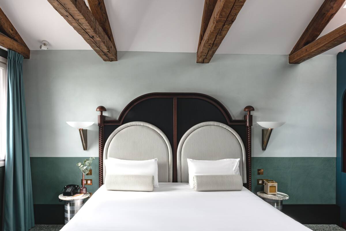 A hotel room with a large bed, two bedside lamps, a nightstand with a phone, and a small table with a lamp.