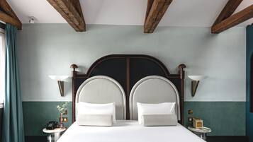 Una habitación de hotel con una cama grande, dos lámparas de noche, una mesita de noche con un teléfono y una pequeña mesa con lámpara.